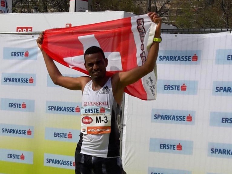 Tadesse Abraham (Photo: Urs Zenger) jubelt mit Schweizer Fahne nach seinem 2. Rang beim Wien-Marathon 2019