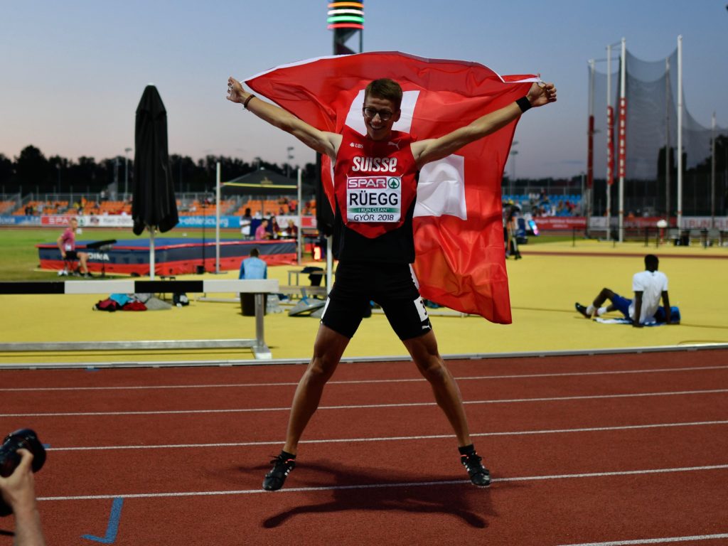 Nick Rüegg macht nach seiner Bronzemedaille über 110 m Hürden an der U18-EM in Györ einen Freudensprung mit der Schweizer Fahne in der Hand